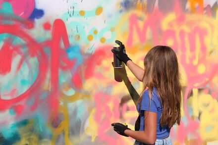 Das Bild zeigt ein Mädchen beim Graffiti-Sprühen.